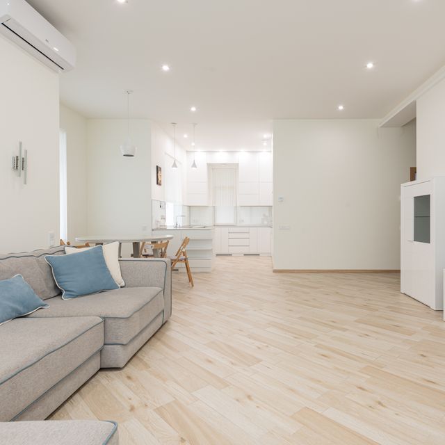 Großes Wohnzimmer mit offener Küche und hellbraunem Vinylboden in Holzoptik