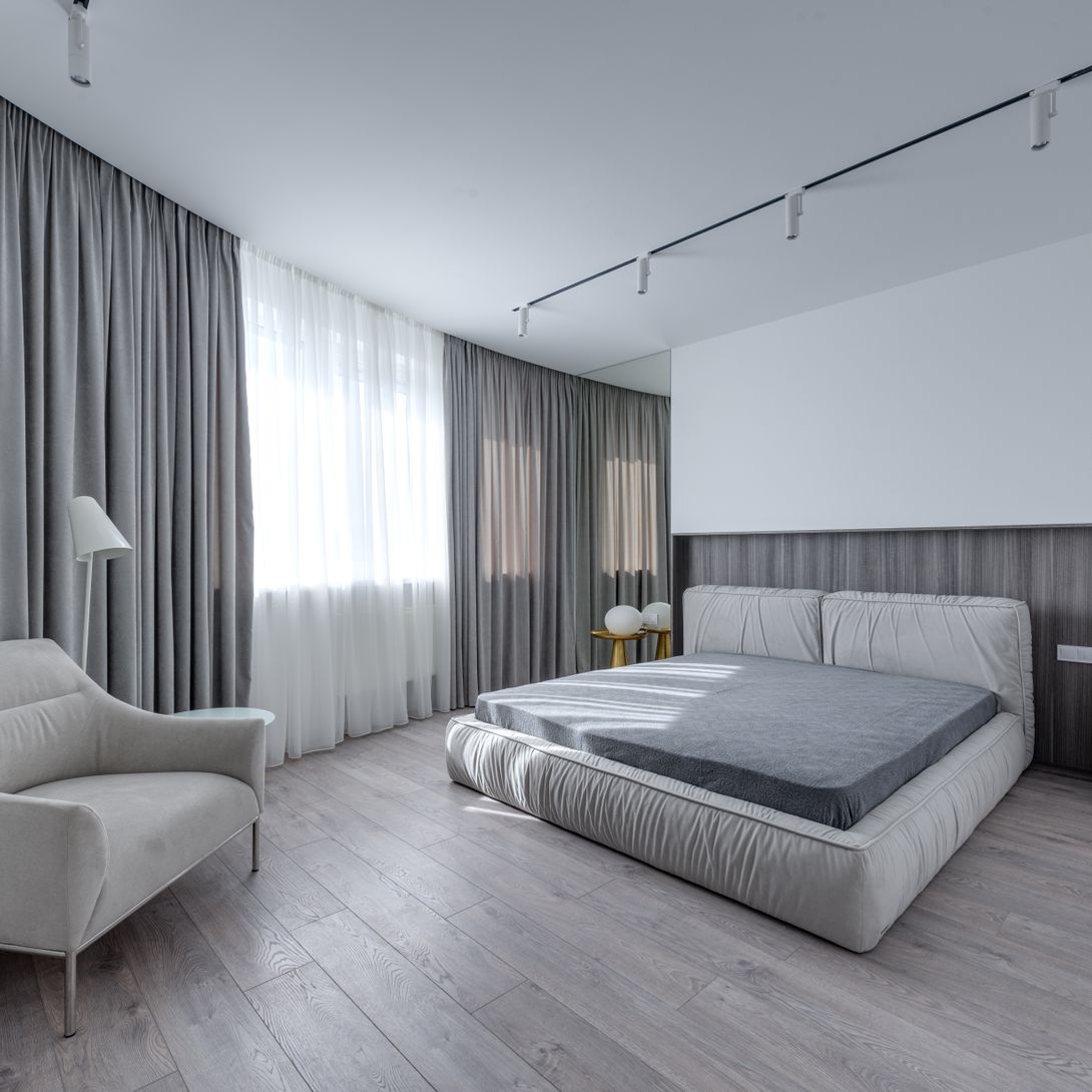 Schlafzimmer mit grauen Möbeln und hellgrauem Designboden in Holzoptik