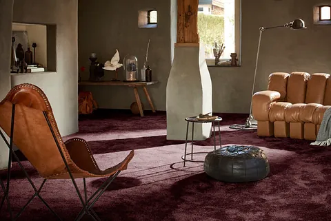 Wohnzimmer mit dunkelroten Teppich und Hellbrauner Ledercouch