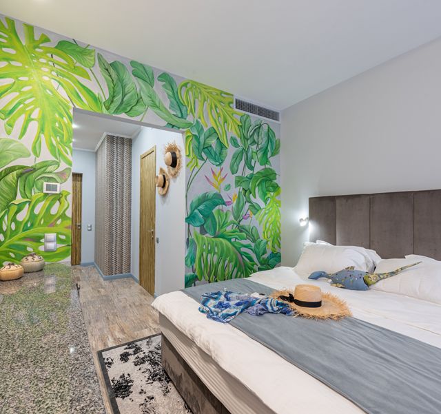 Blätter auf einer Mustertapete verwandeln ein Schlafzimmer in einen Dschungel